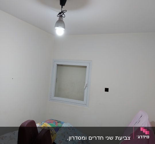 חדר עם קירות צבועים בלבן ומנורה תלויה